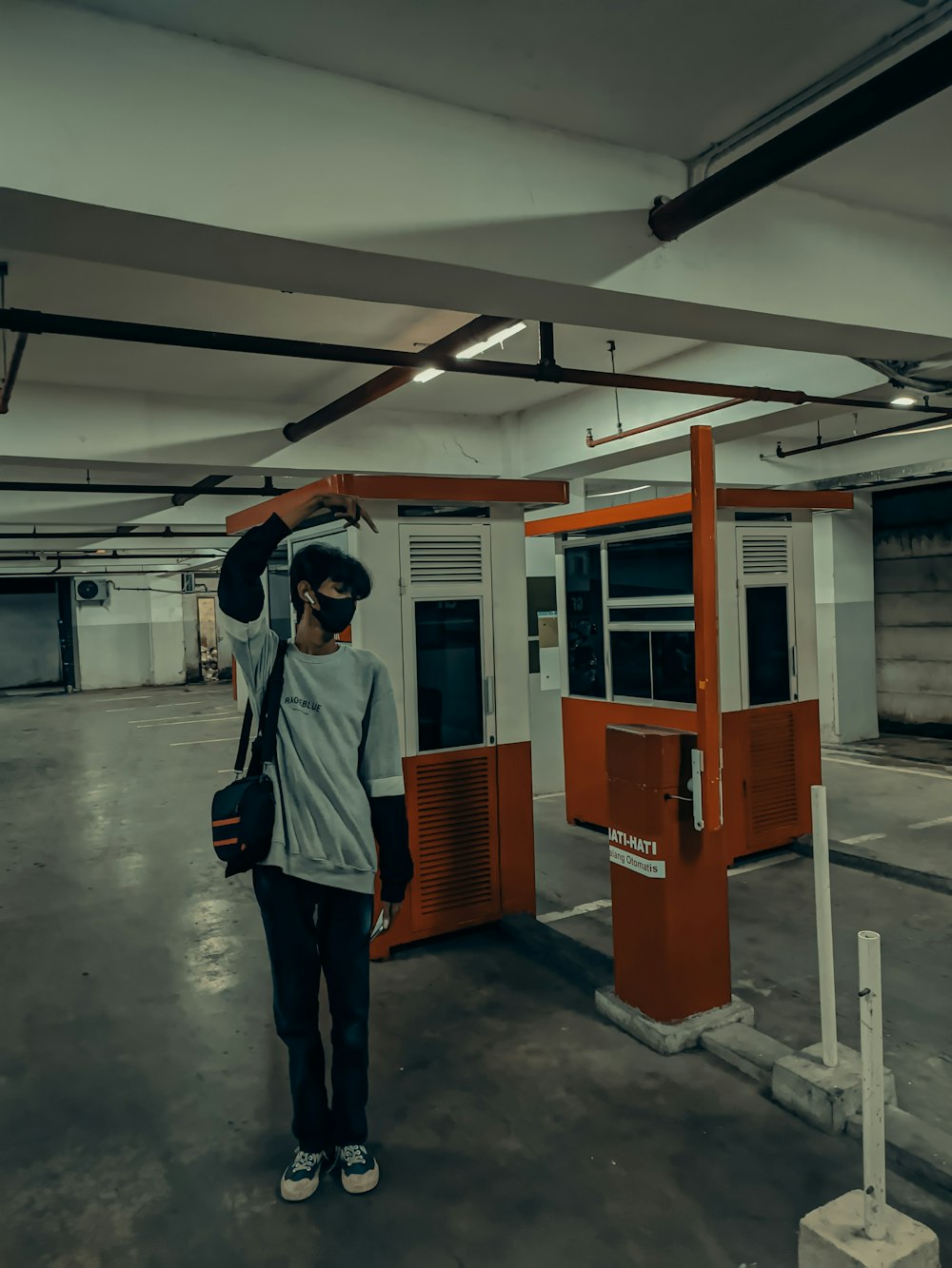 a man standing in a parking garage holding a bag