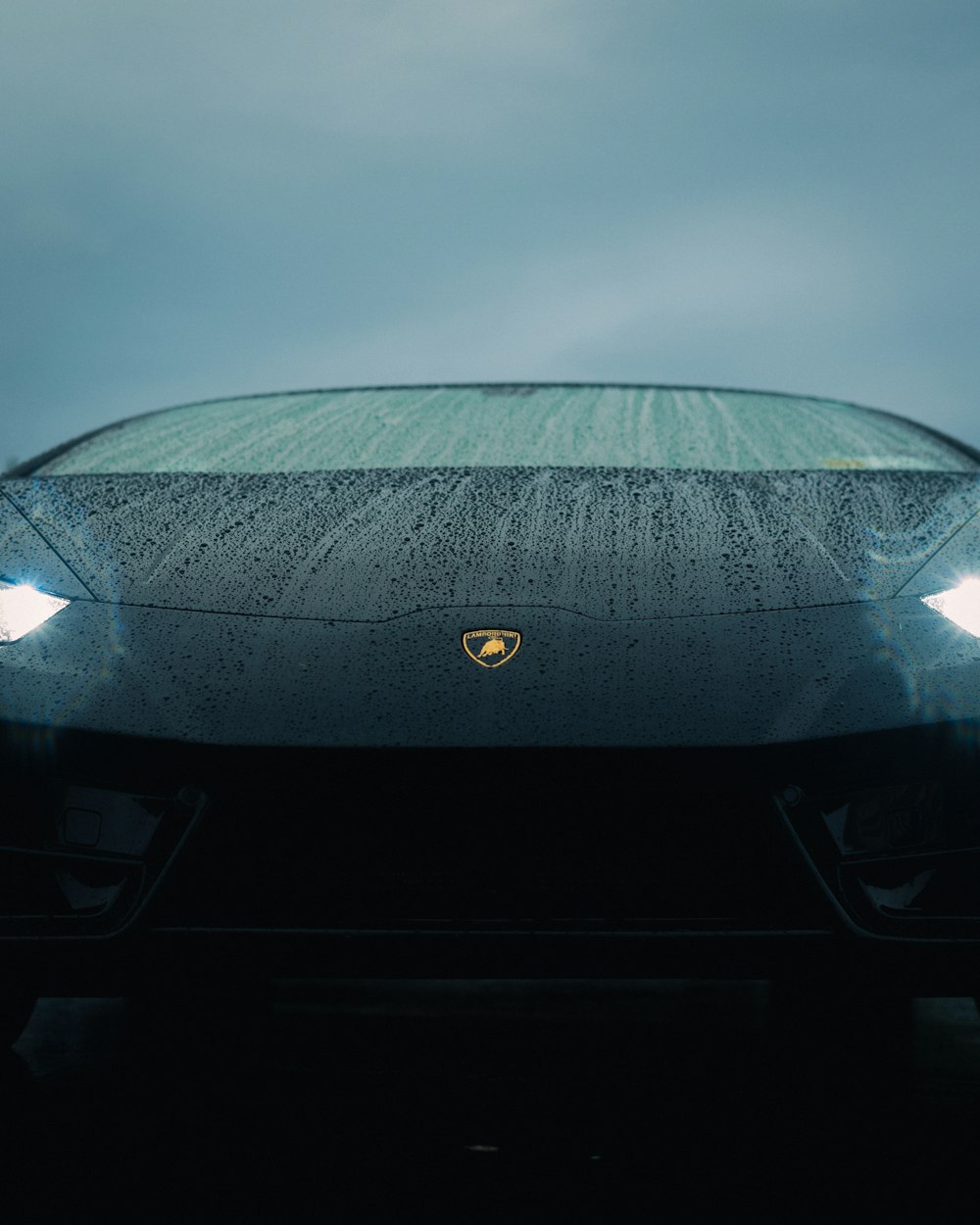 the front of a black sports car on a cloudy day