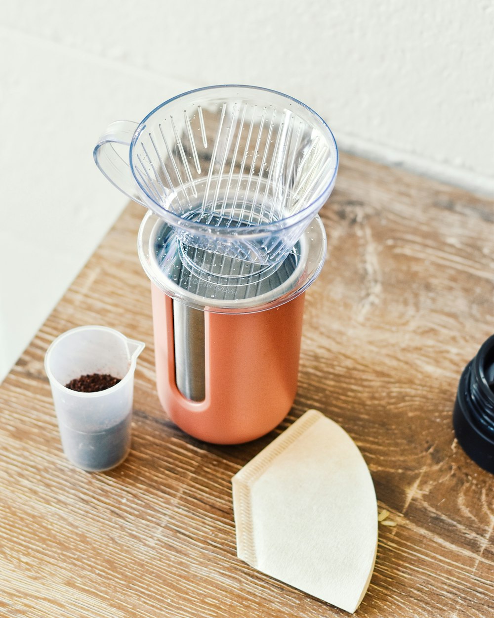 a blender sitting on top of a wooden table next to a cup of coffee