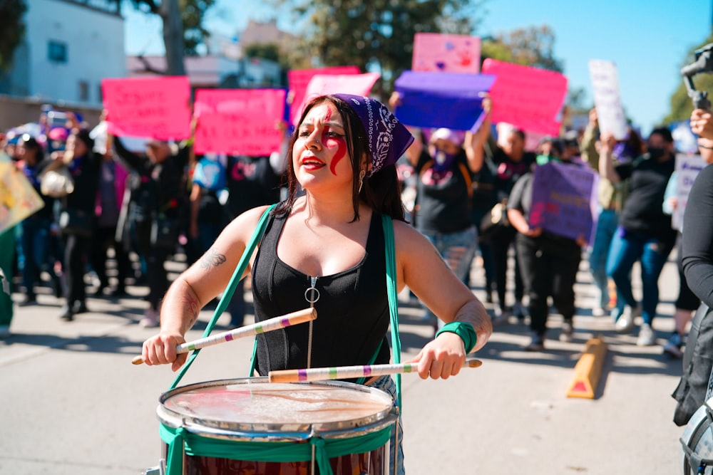 a woman holding a drum in front of a group of people