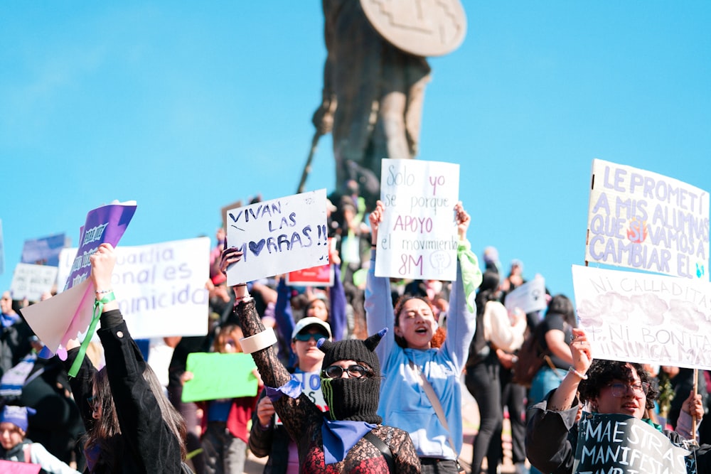 a group of people holding up signs in front of a statue