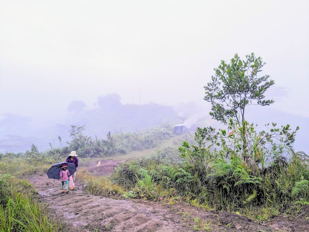 a woman walking up a dirt path in the fog