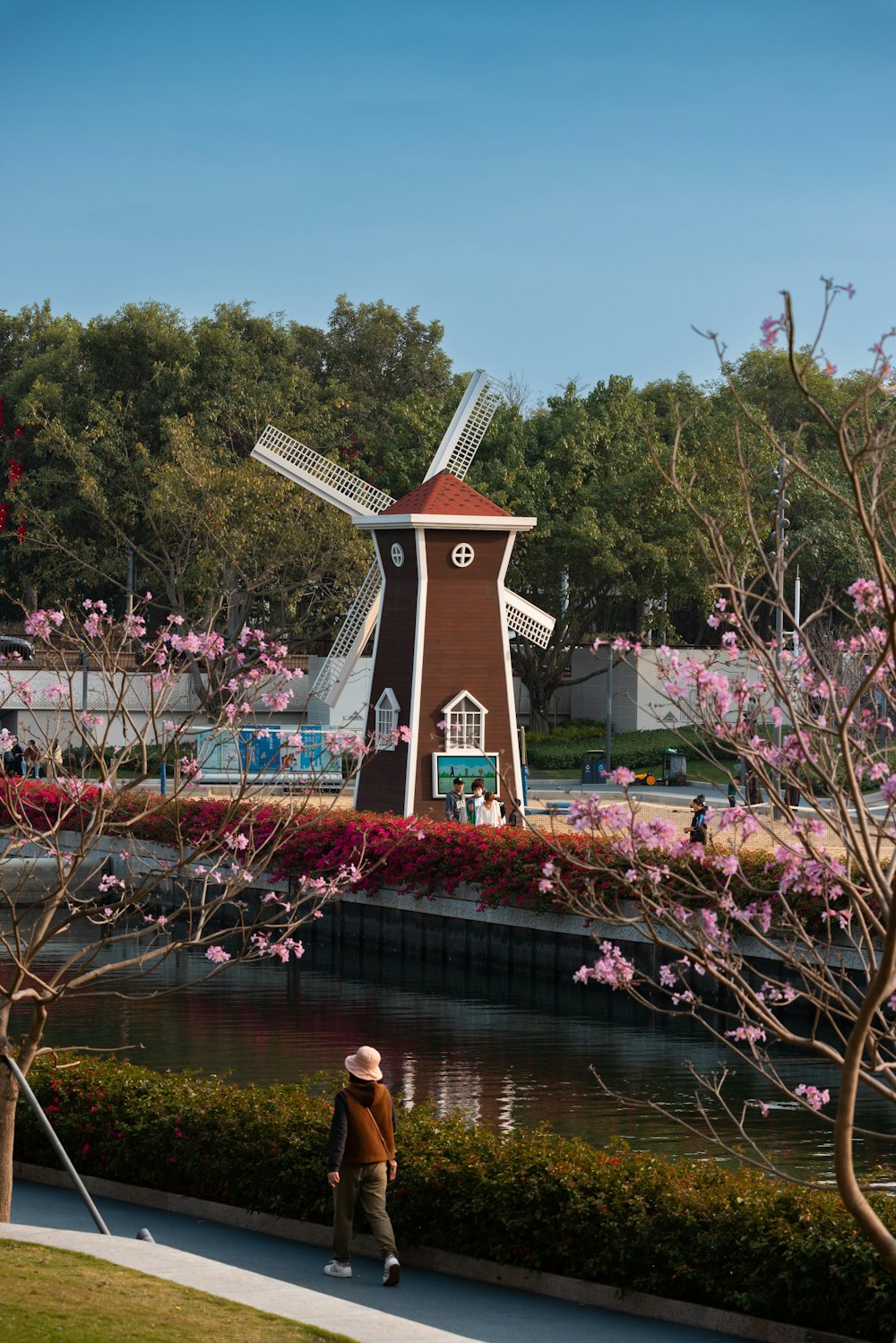 a woman walking down a sidewalk past a windmill