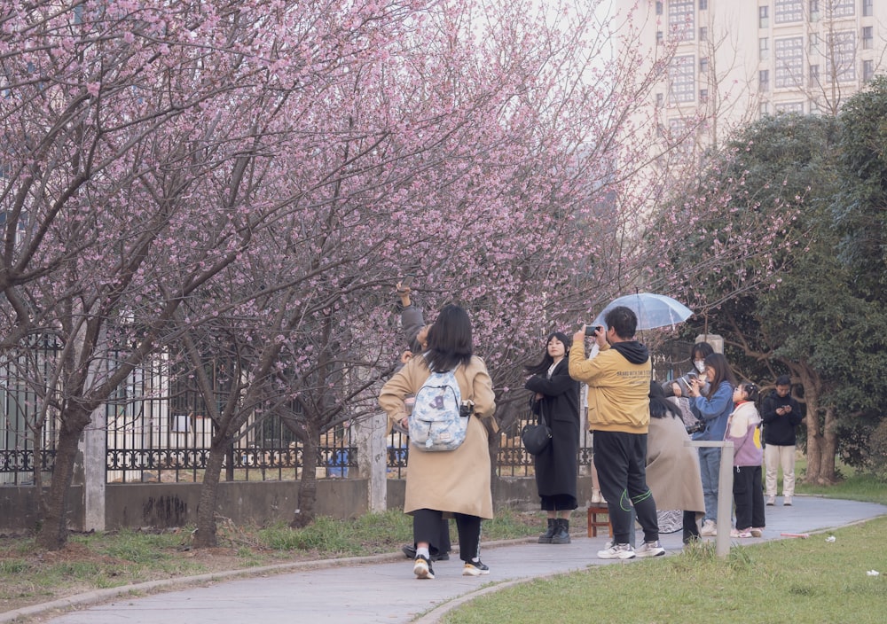 a group of people walking down a sidewalk with umbrellas