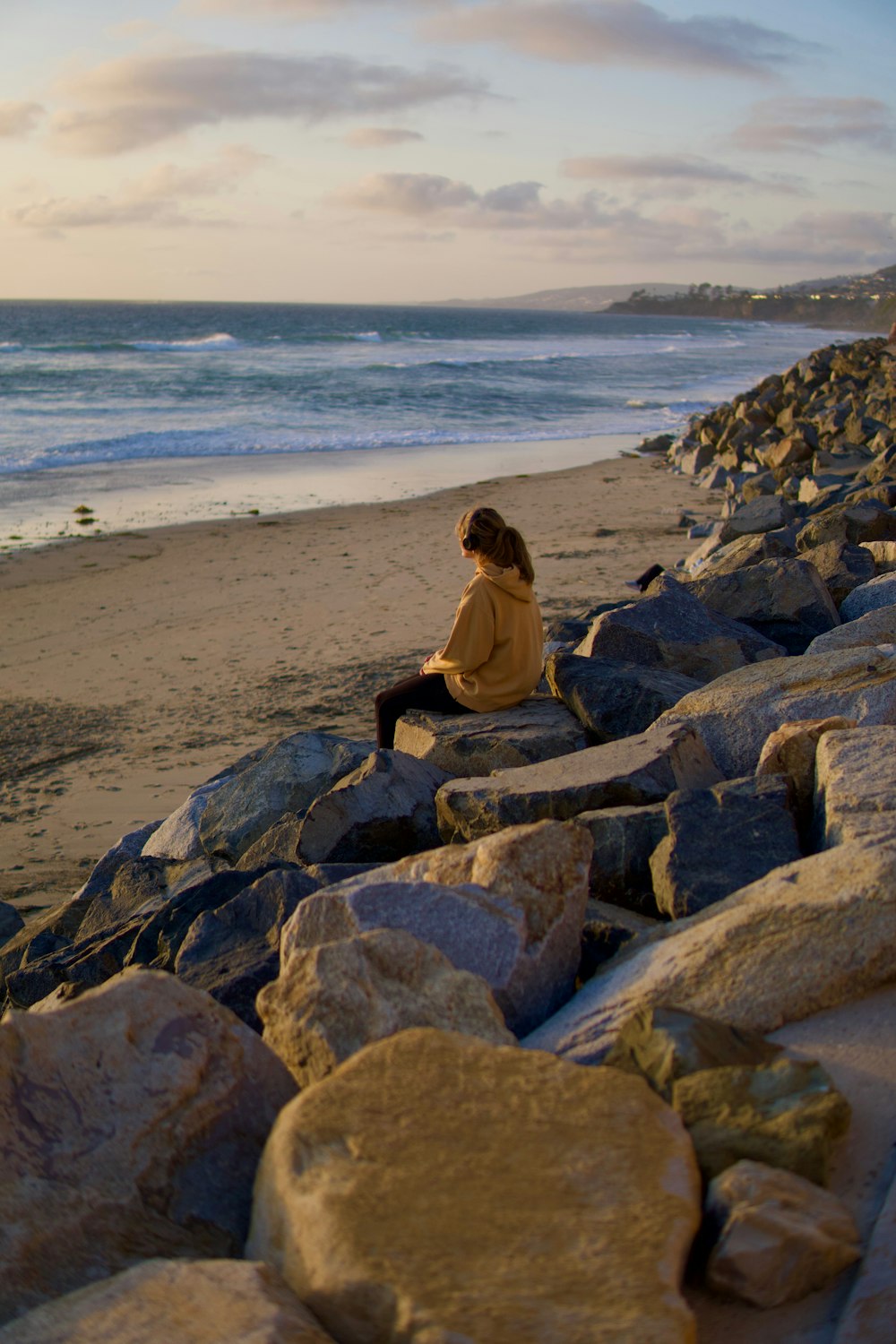 a woman sitting on rocks on the beach