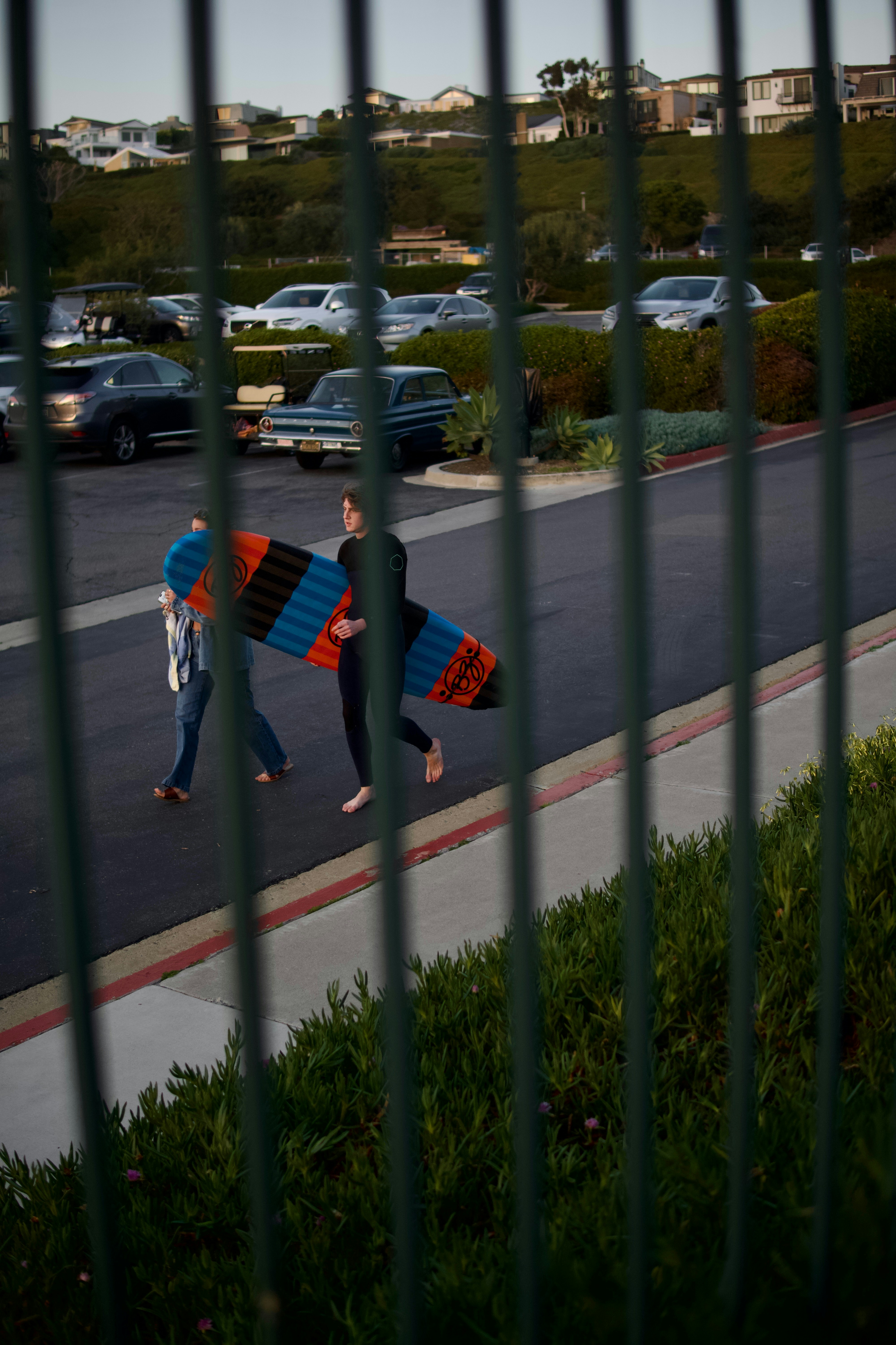 a couple of people walking down a street holding surfboards