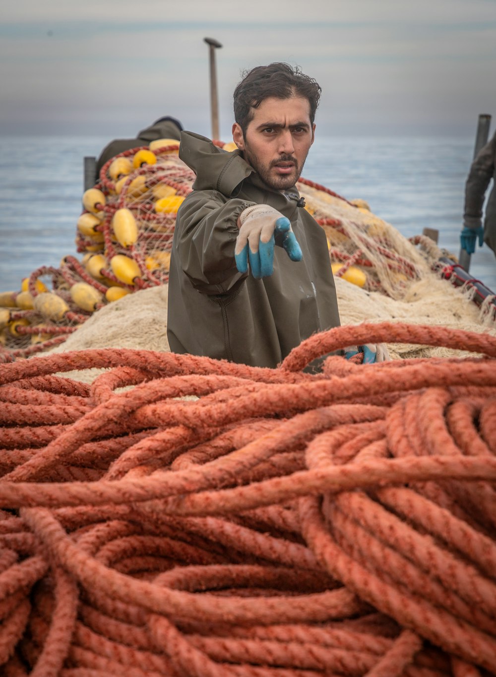 a man standing next to a pile of rope