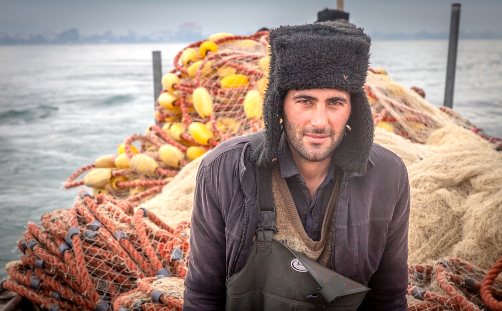 a man standing next to a pile of fishing nets