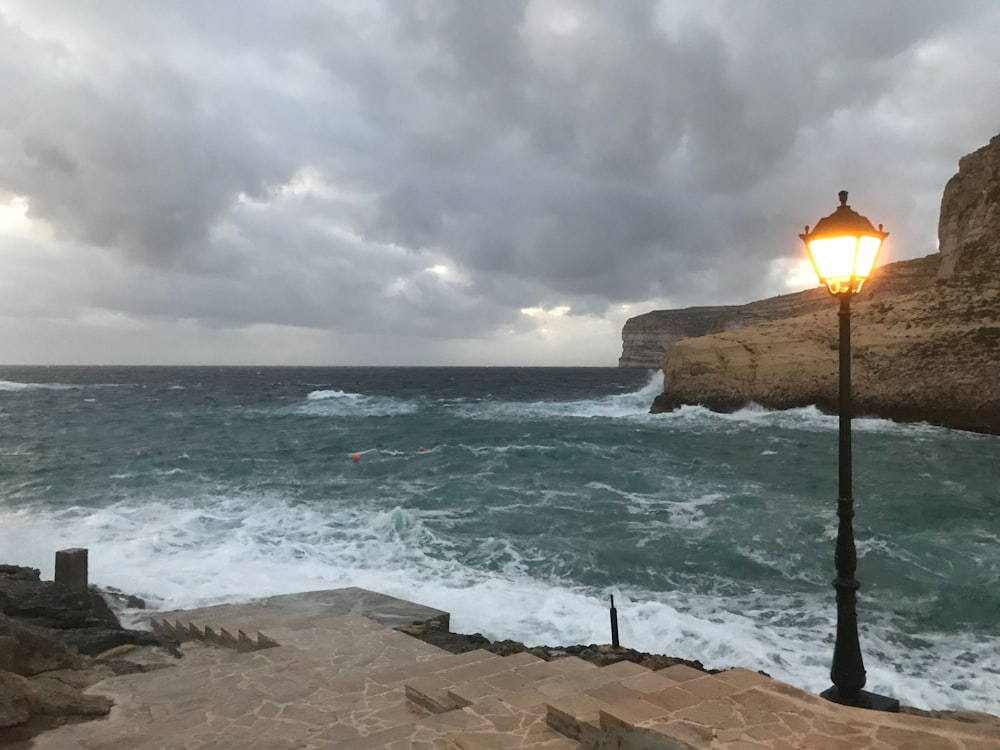 a street light sitting on the side of a cliff next to the ocean