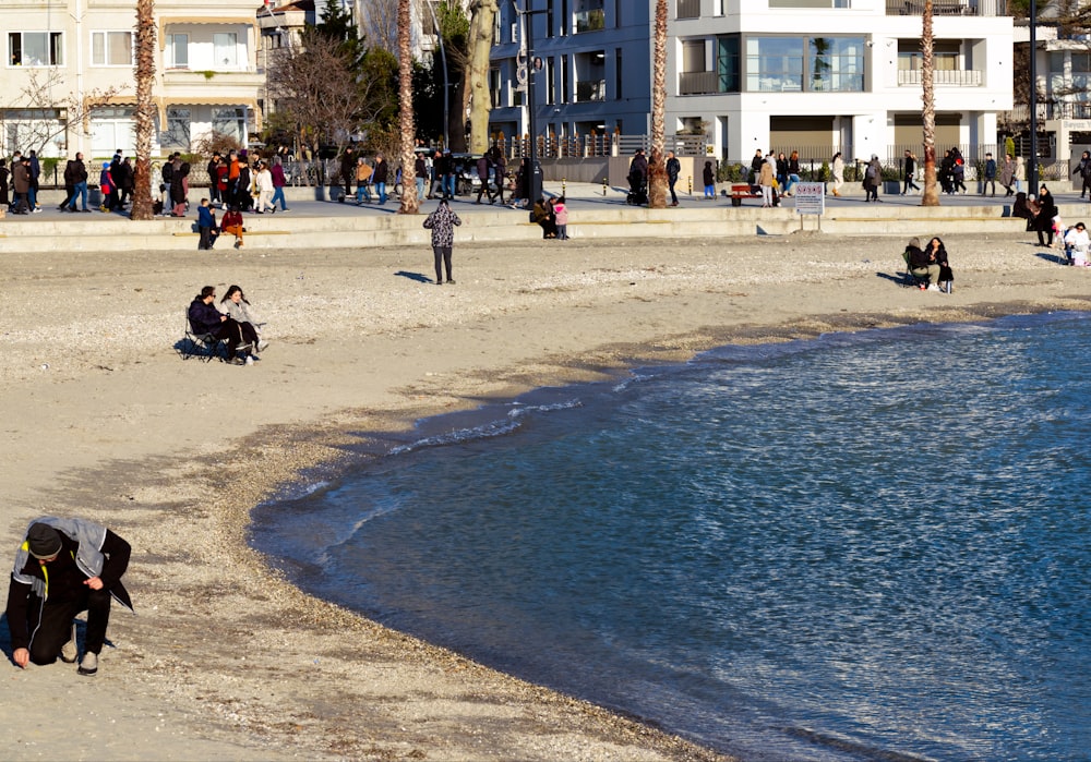 Un grupo de personas sentadas en una playa junto a un cuerpo de agua
