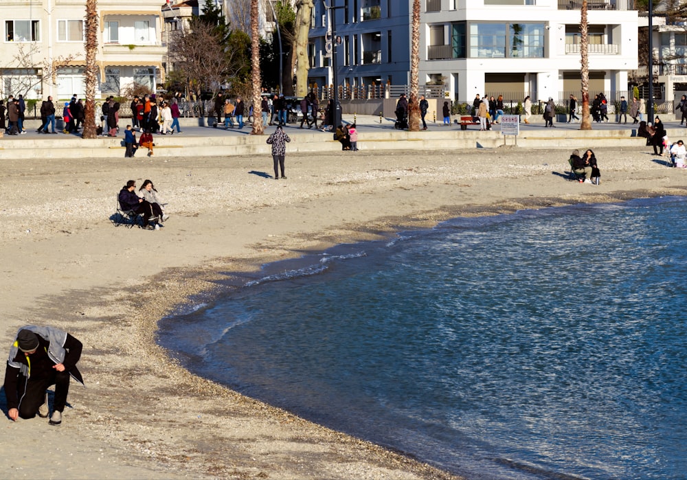 a group of people sitting on a beach next to a body of water