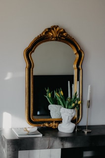 a mirror and a vase with flowers on a table