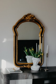 a mirror and a vase with flowers on a table