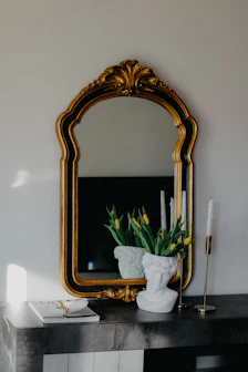 a mirror and a vase with flowers on a table