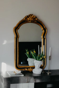 a mirror and a vase with flowers on a table