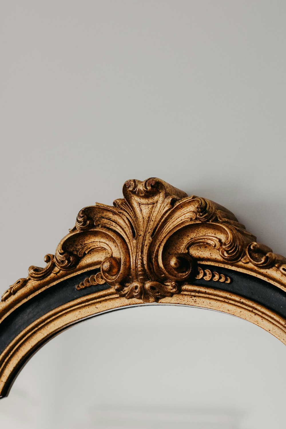 a gold and black ornate mirror against a white wall