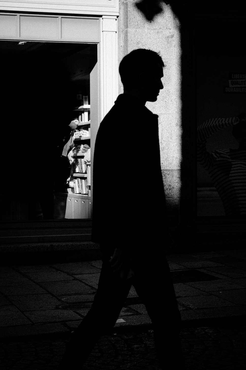 a man walking down a street next to a tall building