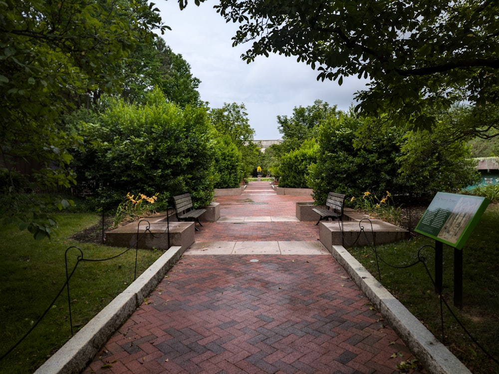 a brick walkway with benches and a sign