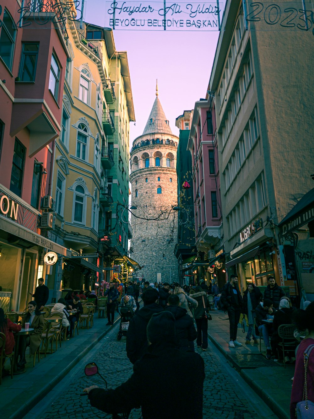 a group of people walking down a street next to tall buildings