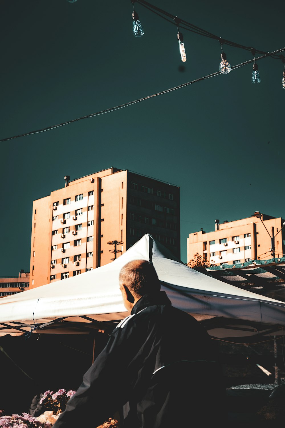 a man standing under a white tent next to tall buildings