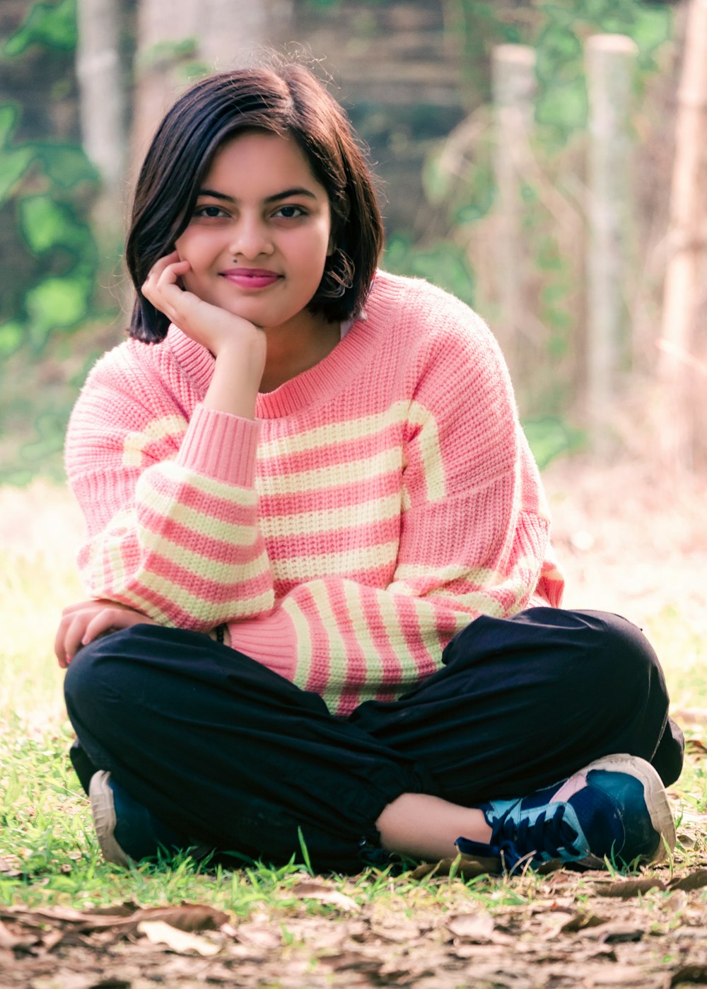 a woman sitting on the ground in the grass