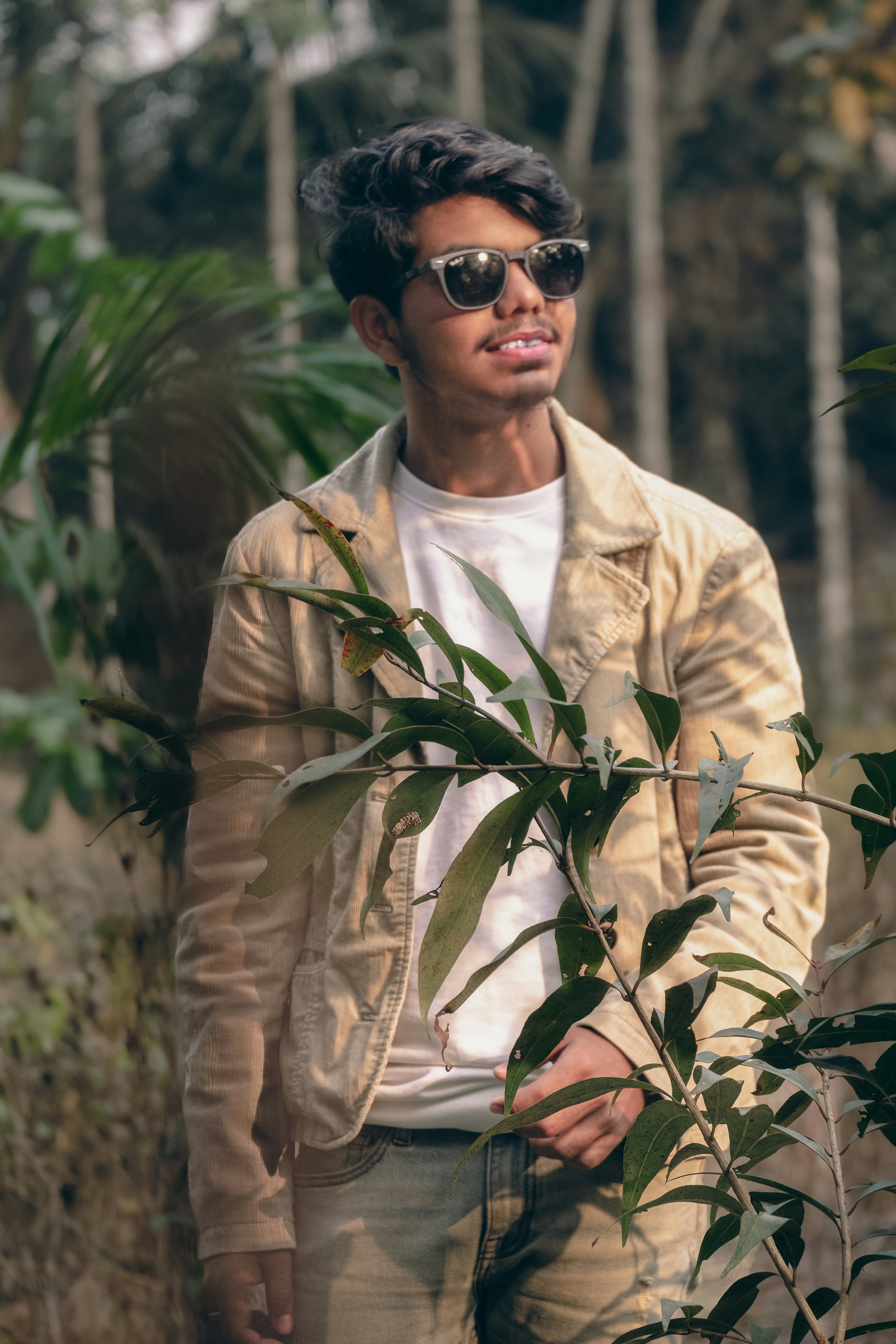 Un homme portant des lunettes de soleil debout à côté d’un arbre