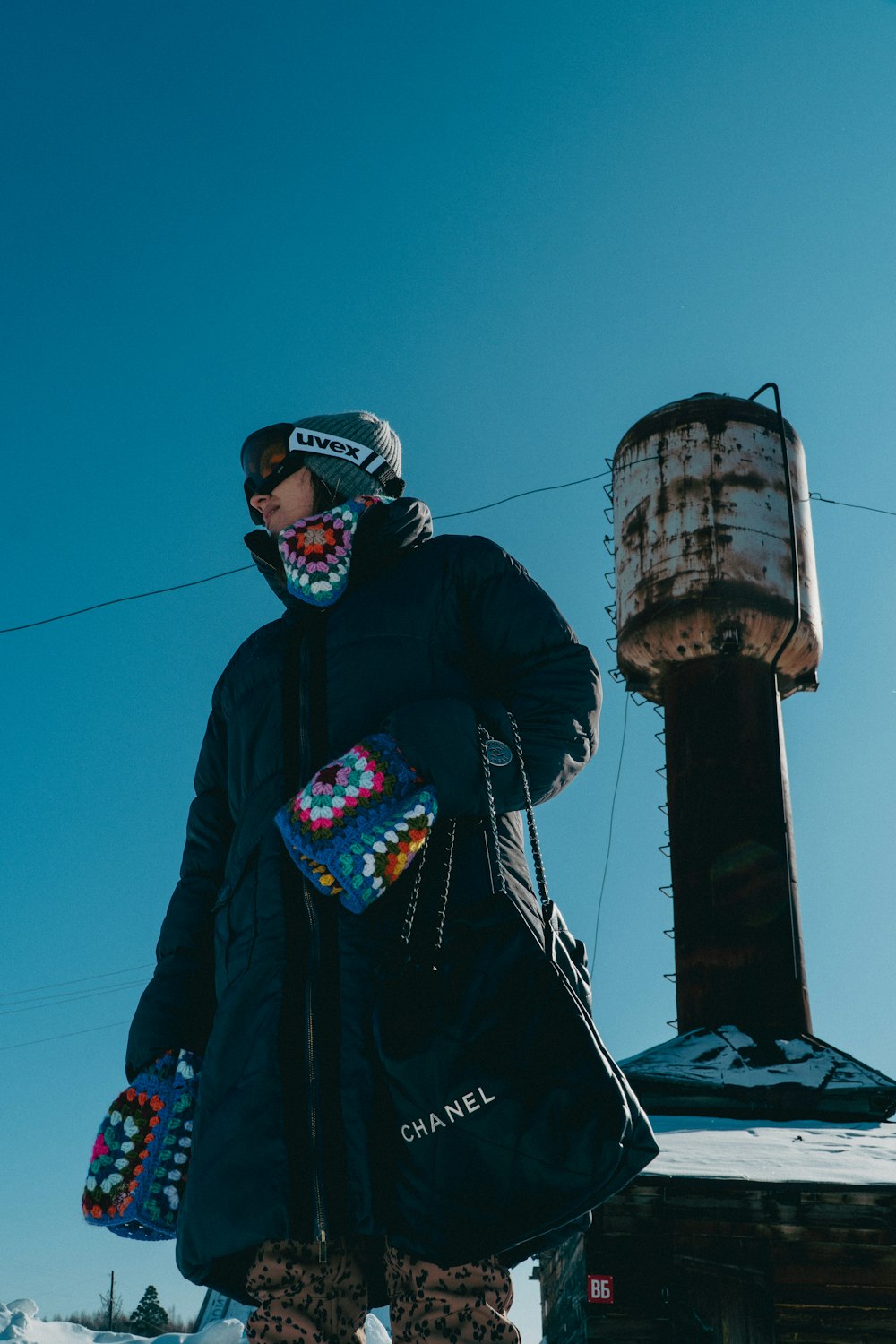 a snowboarder in a black jacket carrying a bag