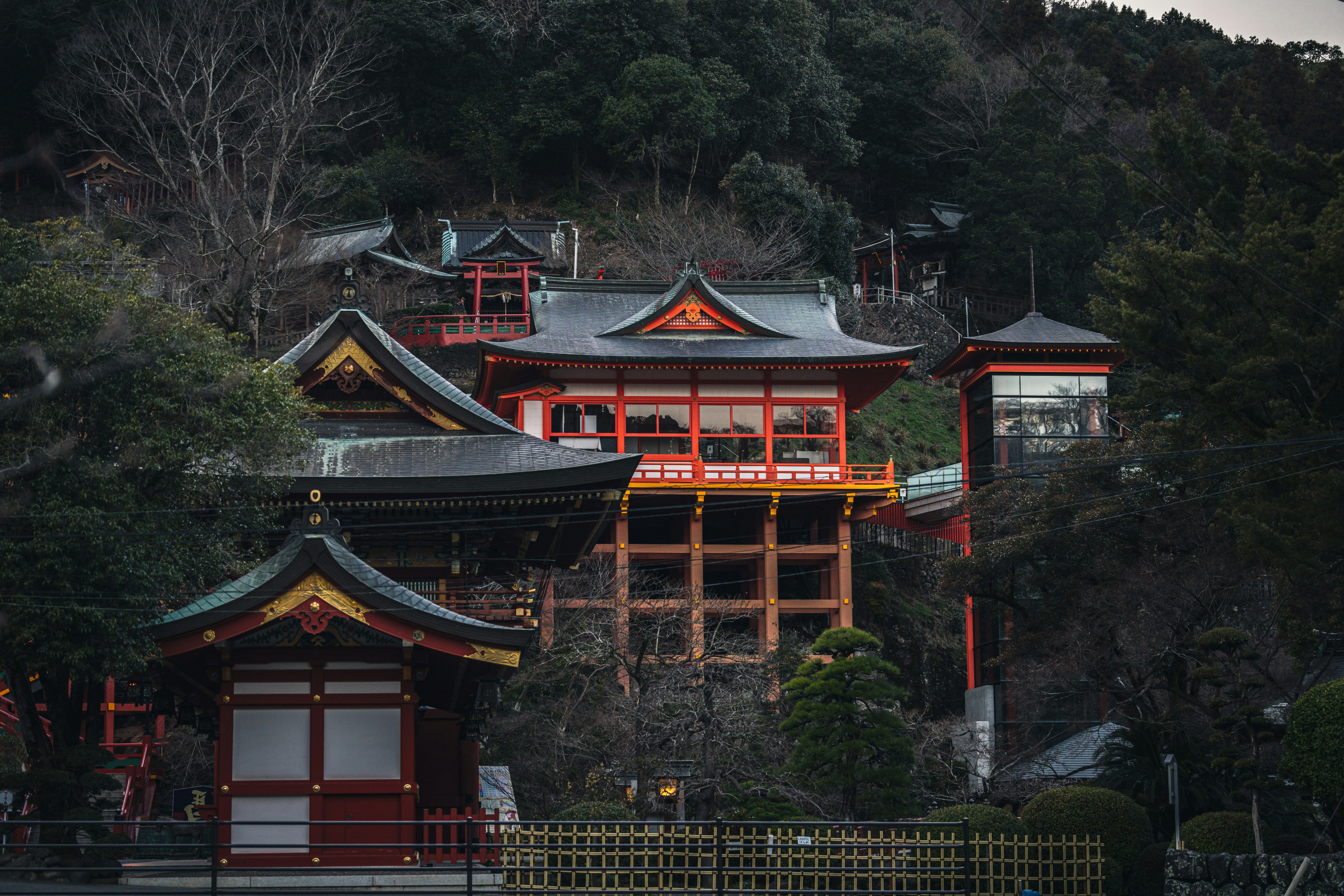 a red and yellow building sitting on top of a lush green hillside
