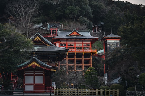 a red and yellow building sitting on top of a lush green hillside