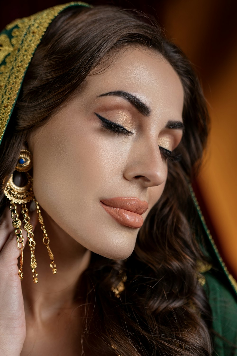 a woman wearing a green veil and gold earrings