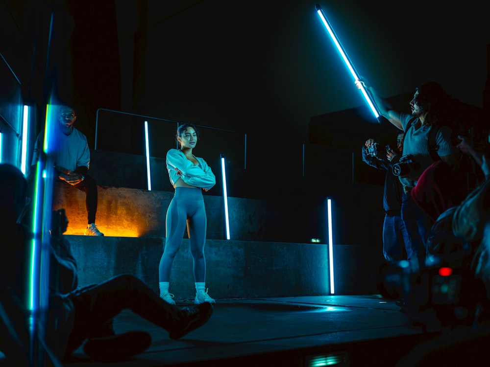 a woman standing on a stage holding a light saber