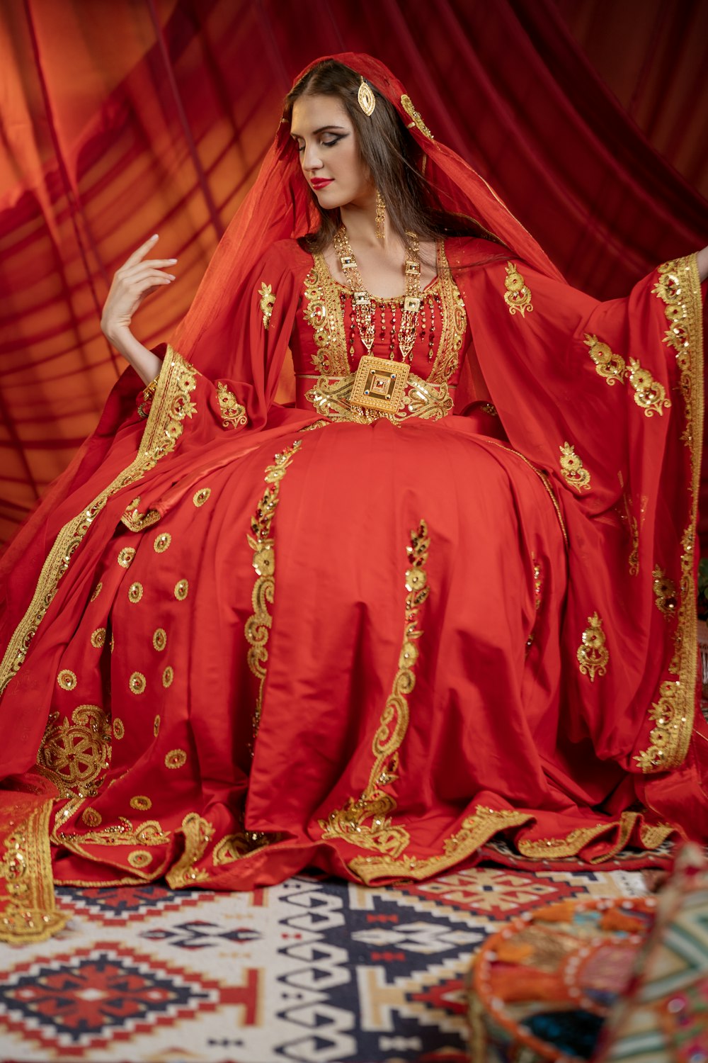 une femme en robe rouge assise sur un tapis
