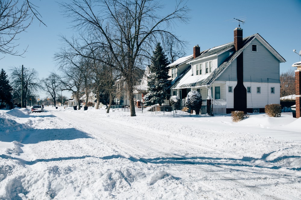 a snow covered street with a house in the background