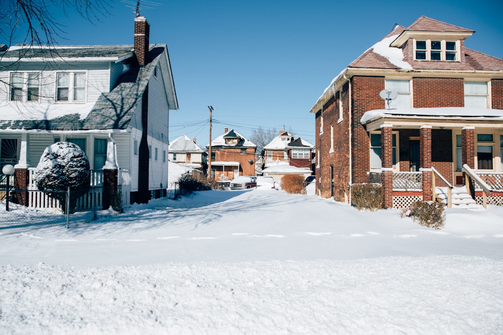 a snow covered street with houses in the background