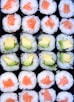 a tray of sushi with avocado and salmon