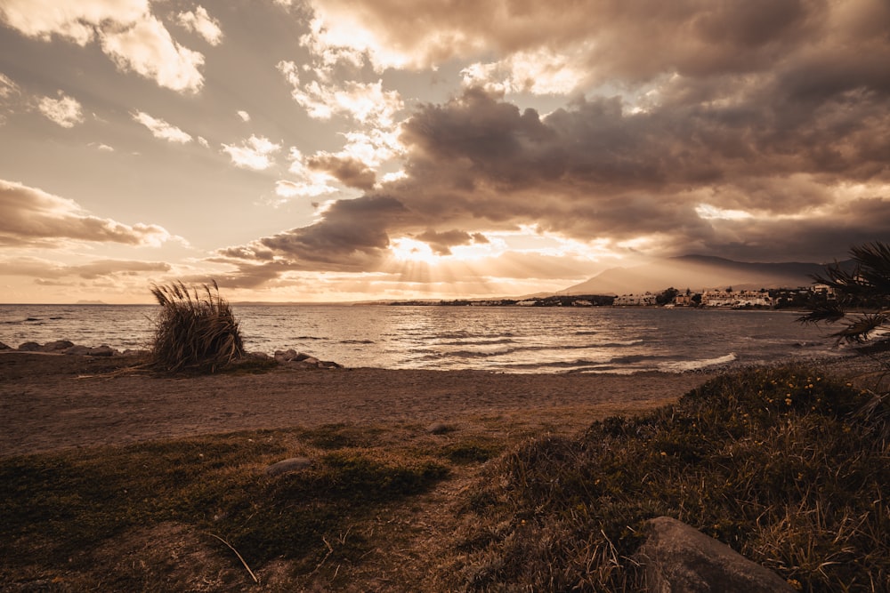 the sun is setting over the ocean on a cloudy day