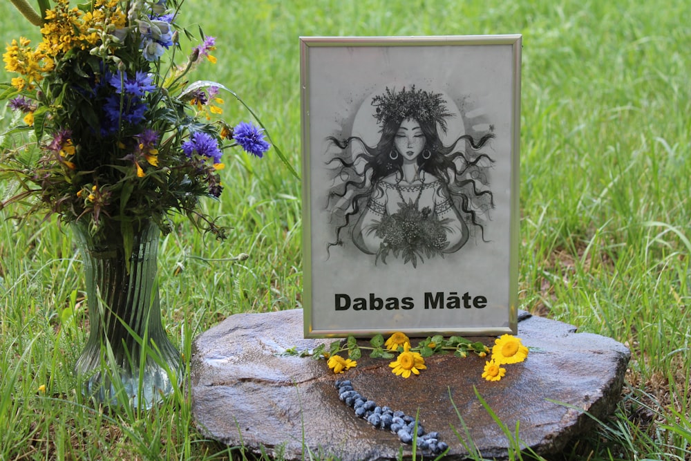 a picture of a woman on a plaque next to a vase of flowers