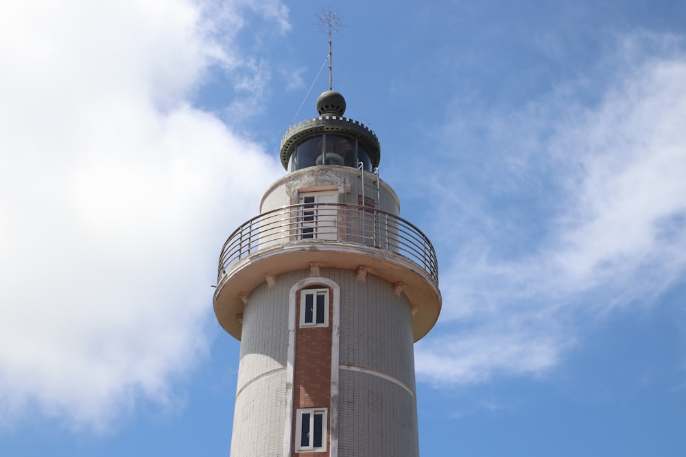 Ein weiß-brauner Leuchtturm mit blauem Himmel im Hintergrund