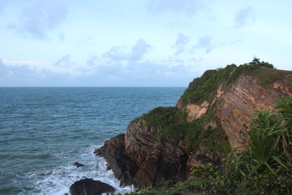 a rocky cliff overlooks the ocean on a cloudy day