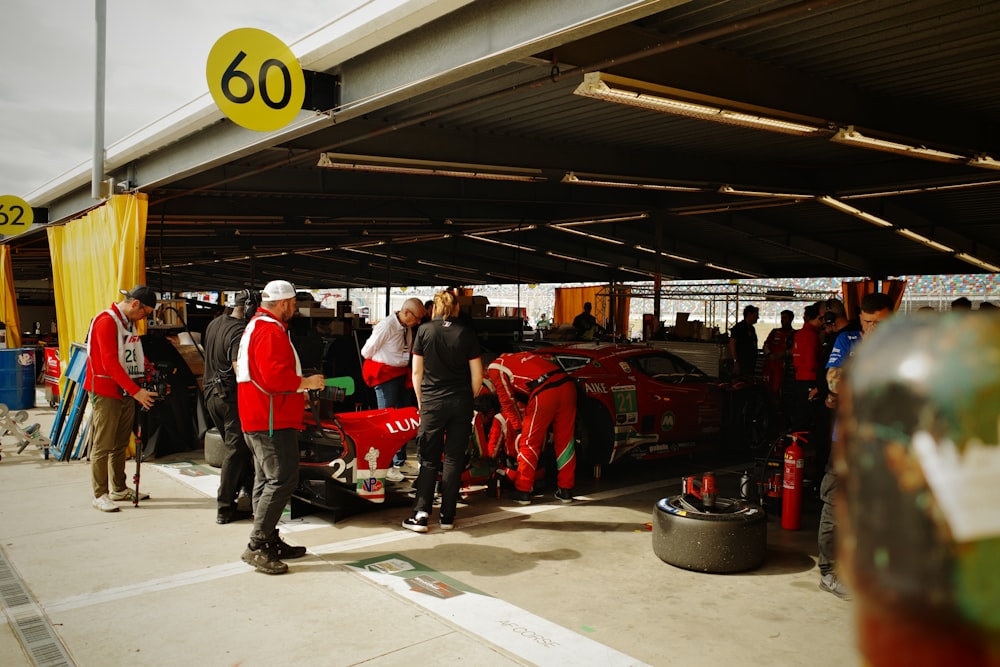 a group of people standing around a red car