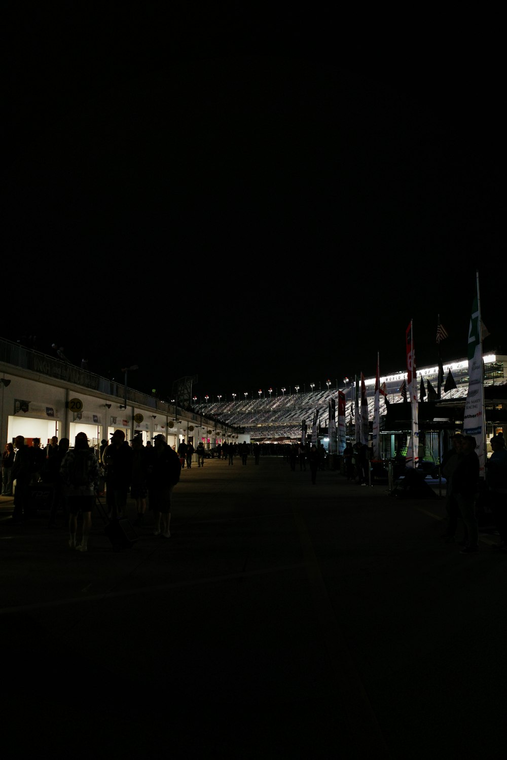 uma multidão de pessoas em pé ao redor de um prédio à noite