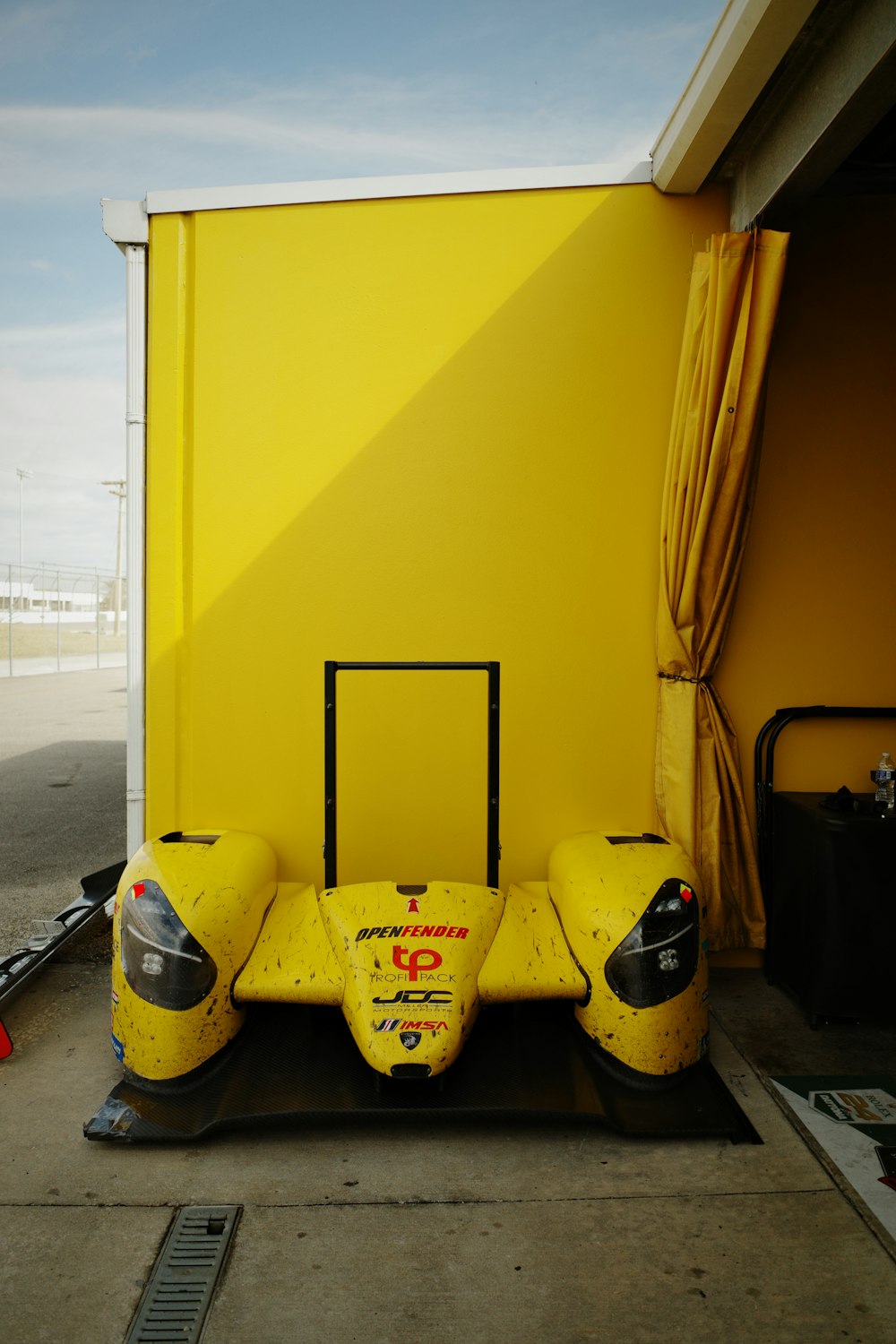 a yellow race car sitting in front of a yellow wall
