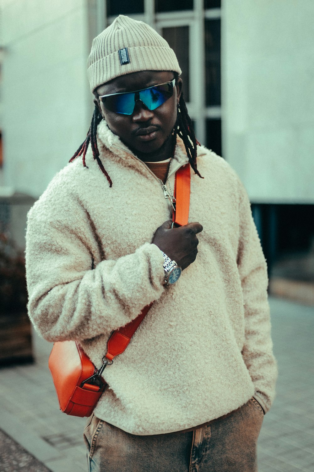 a man with dreadlocks and a beanie is standing on the street