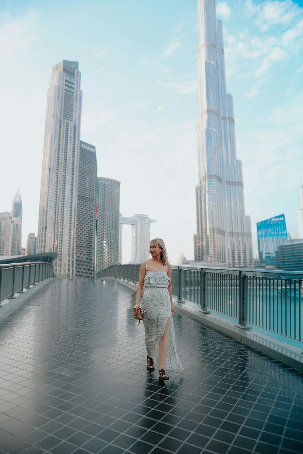 a woman in a white dress walking across a bridge