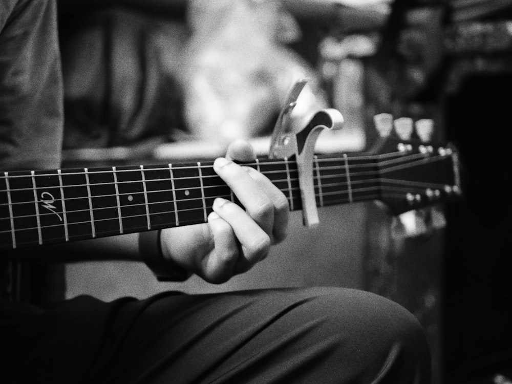 a black and white photo of a person playing a guitar
