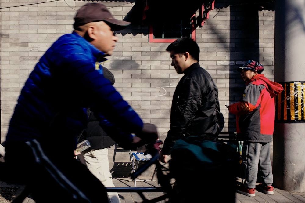 a man riding a bike down a street next to another man