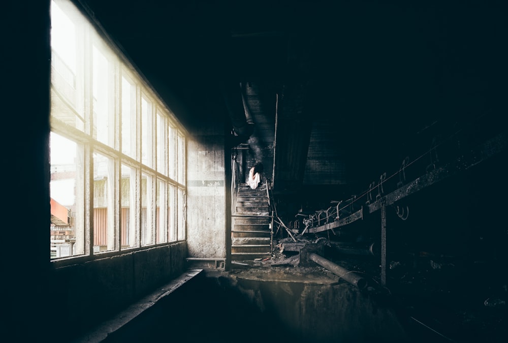 a dark room with a staircase and a window