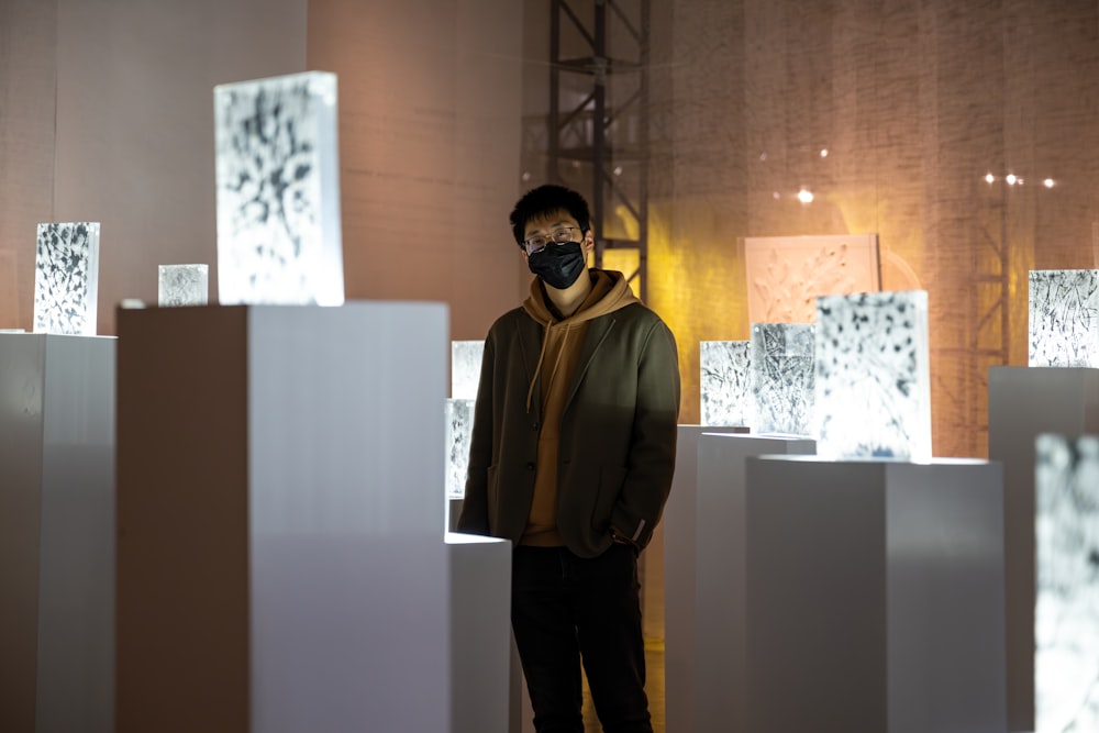 a man wearing a face mask standing in front of a sculpture