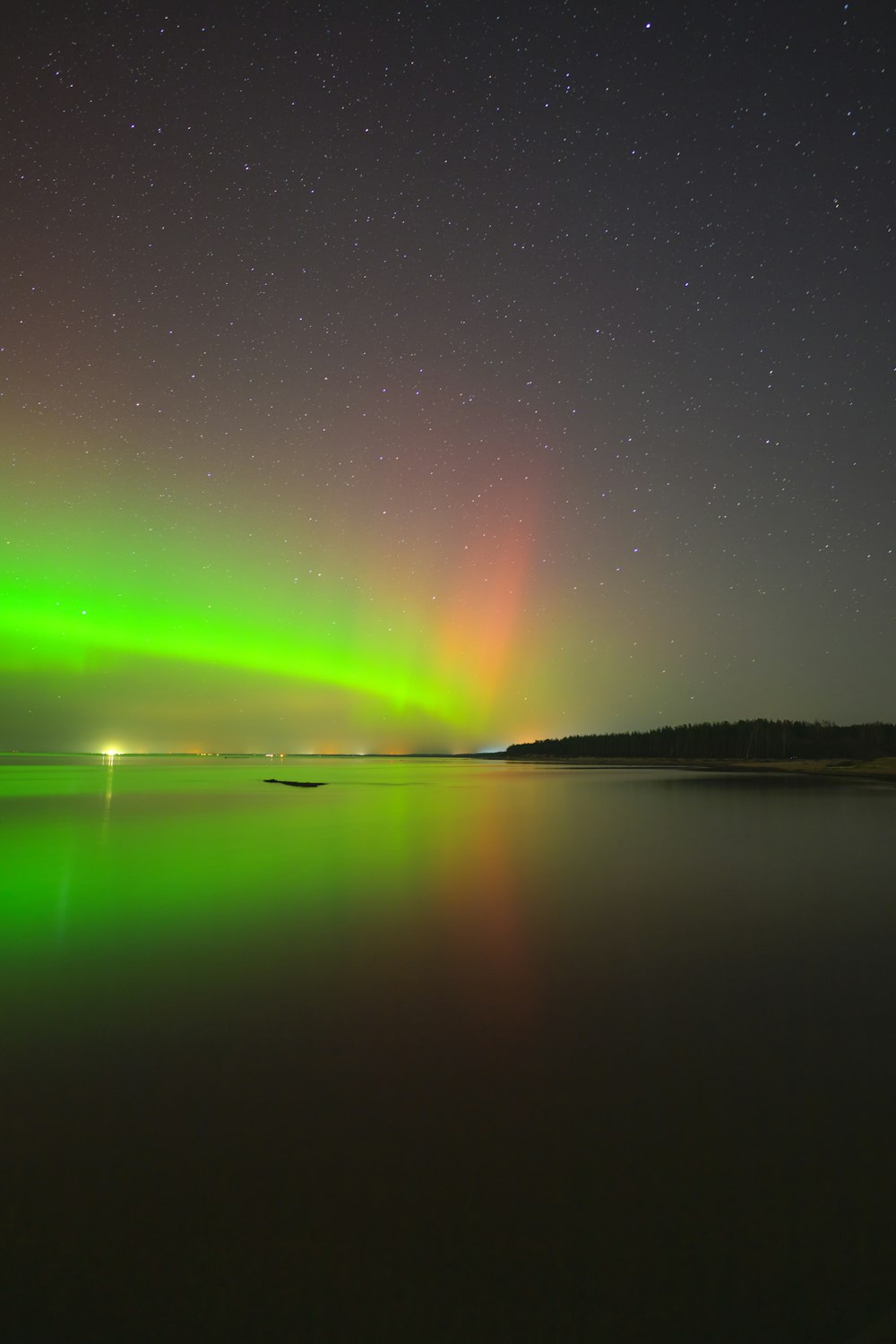 a green and red aurora over a body of water