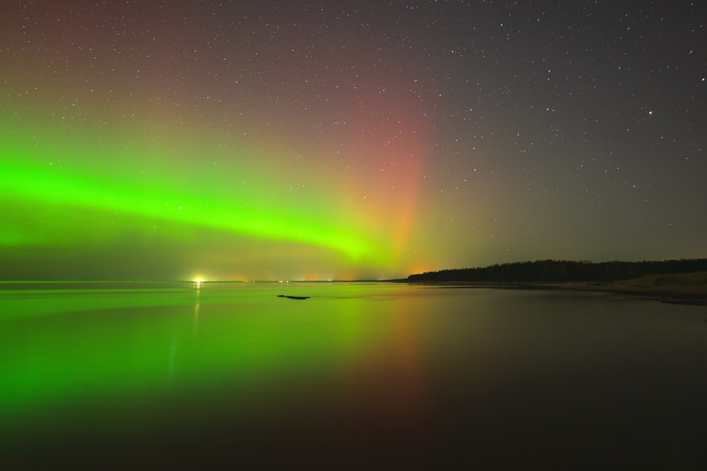 a green and red aurora over a body of water